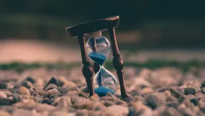 Klepsydra na kamienistym podłożu symbolizująca upływ czasu w kontekście finansów i wydatków.