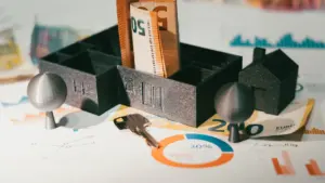 Model domu, klucze i banknoty euro na stole jako symbol finansów nieruchomości.