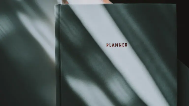 Zamknięty notes typu planner leżący na biurku w świetle dziennym.
