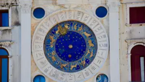 Zegar astronomiczny z symbolami znaków zodiaku na zabytkowej kamiennej ścianie.