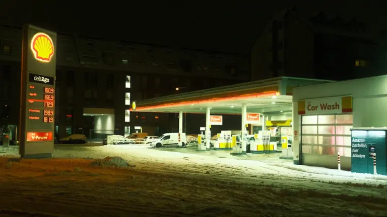 Oświetlony pylon z cenami paliw na stacji benzynowej w nocy.
