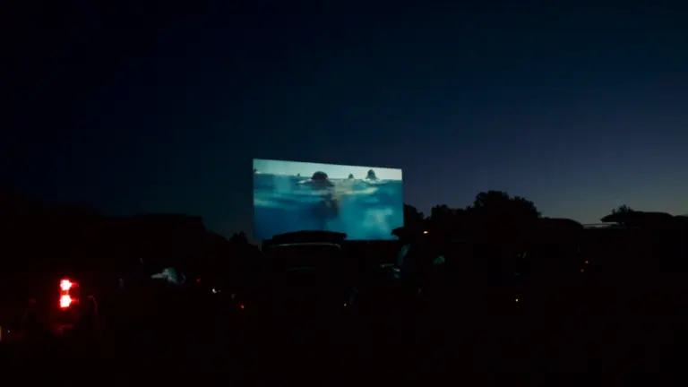 Duży ekran kinowy wyświetlający film w plenerze po zapadnięciu zmroku w Legnicy.